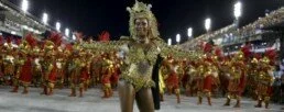 Femme en costume couleur or avec des hommes alignés en rouge et or dans un sambodrome pour le carnal de Rio